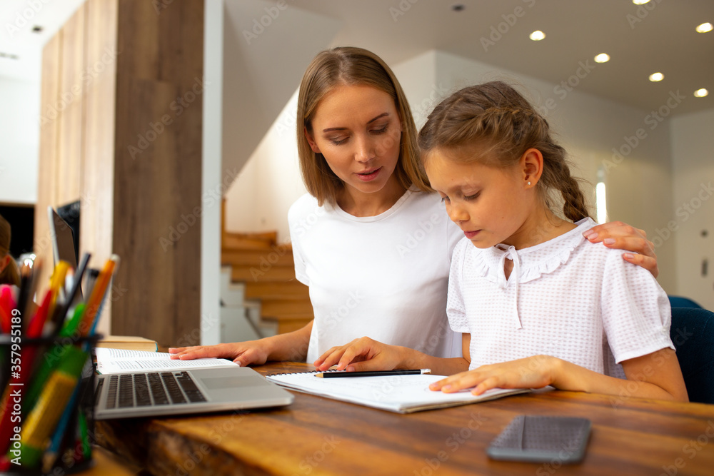 Loving mother helping her daughter to study at home Loving mother helping her daughter to study at home