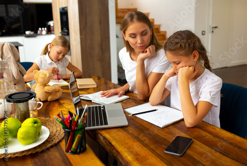 Charming young woman helping daughter to do homework