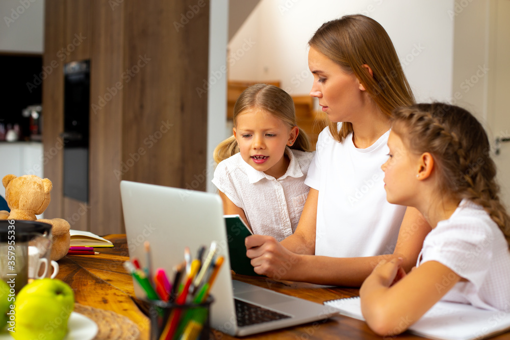 Loving mother helping adorable daughters to study at home Loving mother helping adorable daughters to study at home
