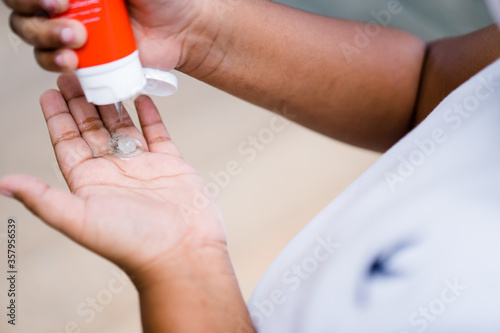 Close up of ameican african kid hands applying alcohol gel at school.Coronavirus prevention medical hand sanitizer gel for hand hygiene coronavirus covid-19 protection.Hand sanitizer alcohol gel.
