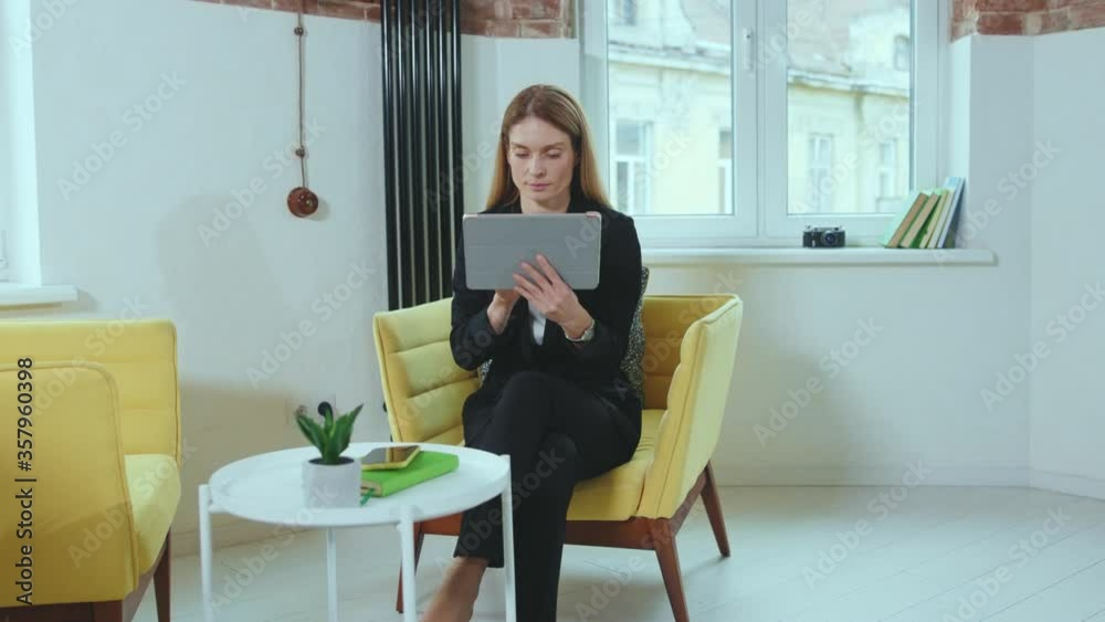 Happy woman sits on sofa using tablet computer at home businesswoman business concept online touchscreen beautiful modern close up slow motion Happy woman sits on sofa using tablet computer at home businesswoman business concept online touchscreen beautiful modern close up slow motion
