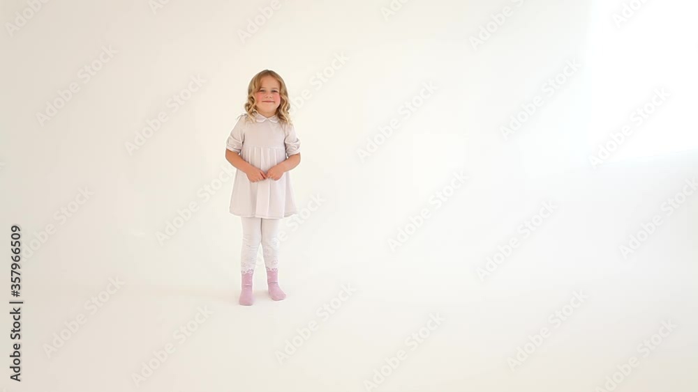 Cute little shy small nice girl child toddler with curly blond hair in white dress drawing big heart in air with fingers Cute little shy small nice girl child toddler with curly blond hair in white dress drawing big heart in air with fingers