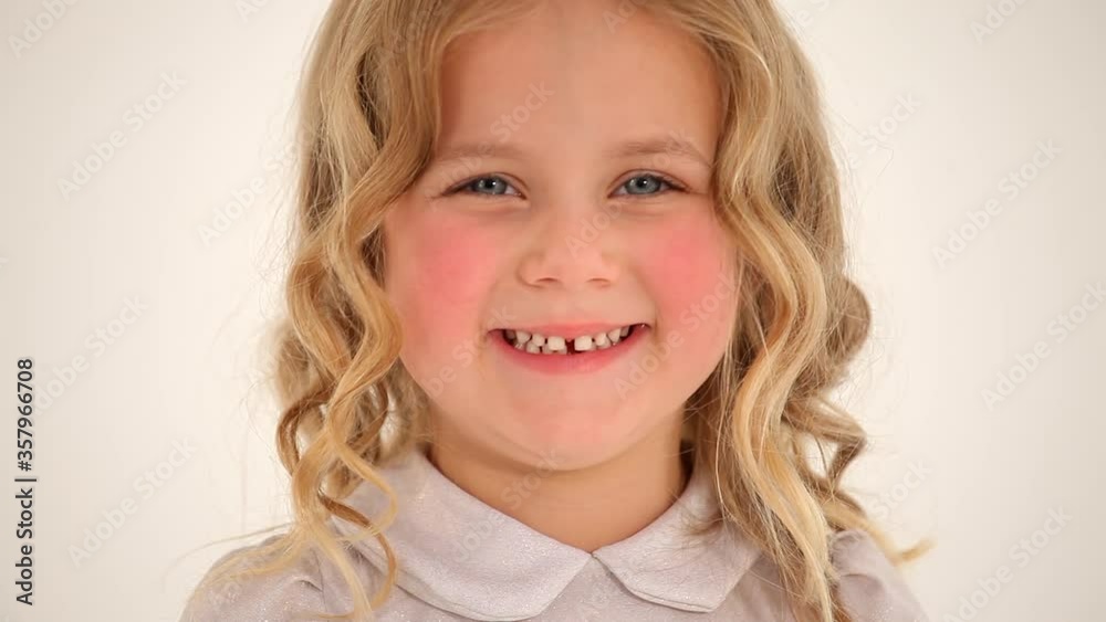 Close up shot of cute small nice little girl toddler child with rosy cheeks curly blond hair looking smiling in camera Close up shot of cute small nice little girl toddler child with rosy cheeks curly blond hair looking smiling in camera