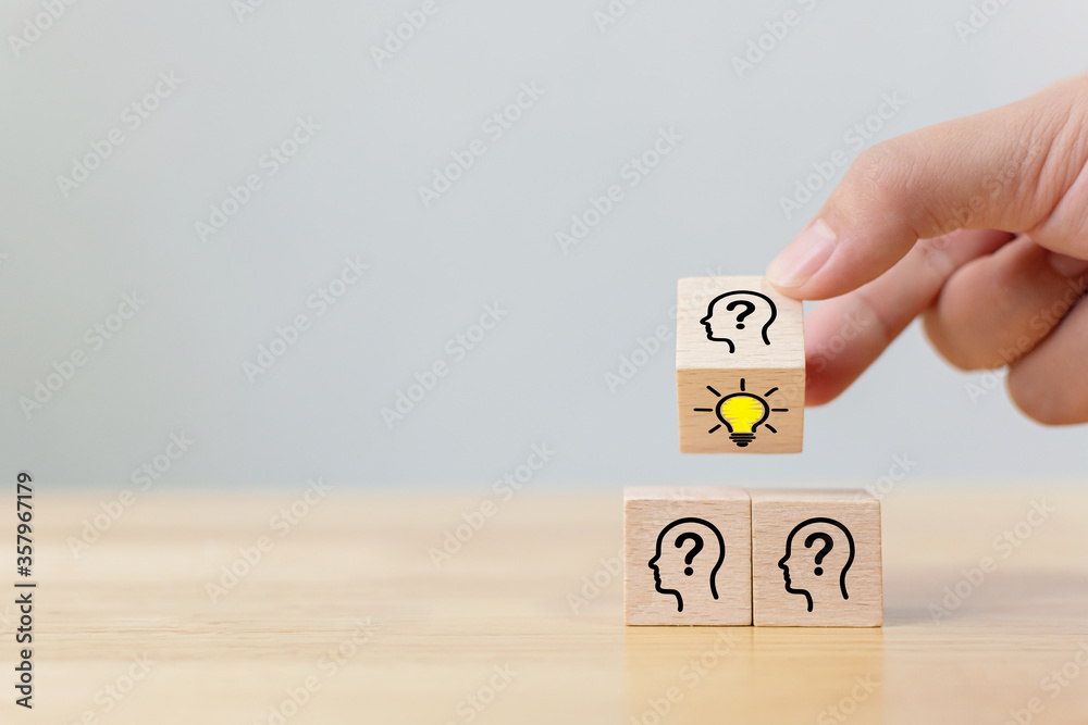 Concept creative idea and innovation. Hand flip over wooden cube block with head human symbol and light bulb icon Concept creative idea and innovation. Hand flip over wooden cube block with head human symbol and light bulb icon