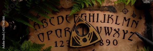 Mystic ritual with Ouija and candles. Devil's board concept, black magic or fortune telling rite with occult and esoteric symbols. Banner.