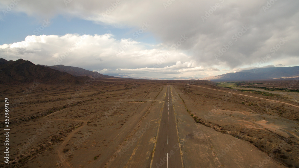 road into the desert. Aerial view of the wide and empty asphalt highway across the mountains. road into the desert. Aerial view of the wide and empty asphalt highway across the mountains.