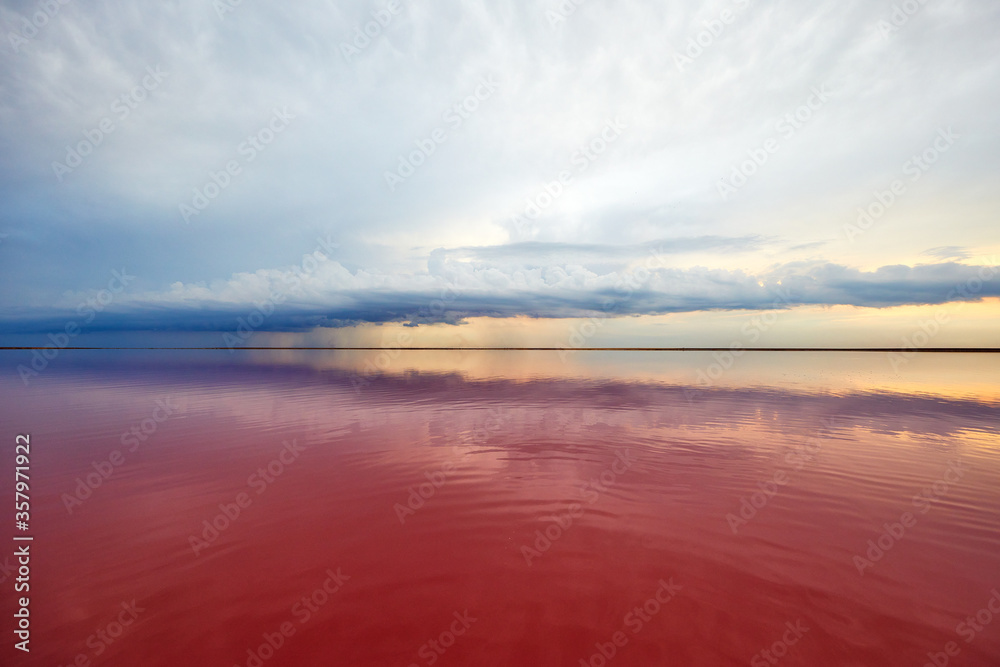 pink lake and sandy beach with a sea bay under a blue sky with clouds