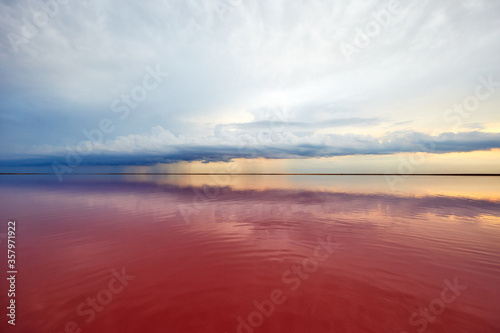 pink lake and sandy beach with a sea bay under a blue sky with clouds