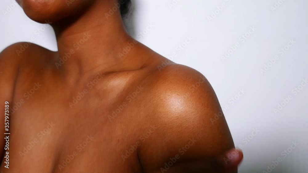 A beautiful young African-American woman applying body cream. Beauty and skin care routine.