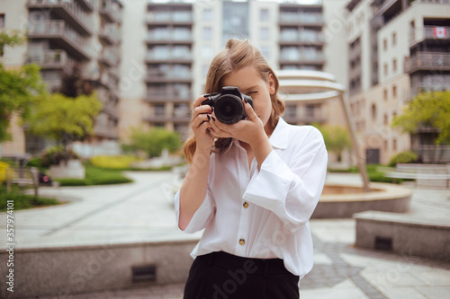 A beautiful girl looks in the viewfinder in the camera, and takes pictures. The blonde learns to photograph and earn money on the photo. 