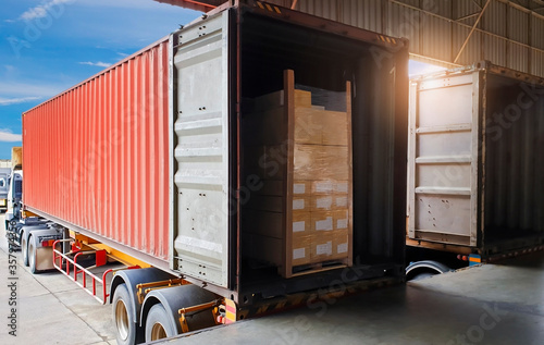 Package Boxes on Pallet Loading into Shipping Cargo Container. Trucks Parked Loading at Dock Warehouse. Supply Chain Shipment Logistics. Cargo Freight Truck Transport. photo