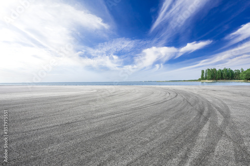 Empty asphalt road and lake under blue sky.