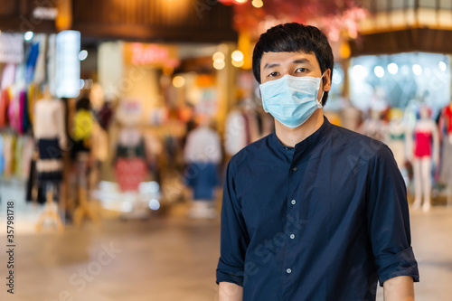 young asian man wearing medical mask at shopping mall for prevention from coronavirus (Covid-19) pandemic. new normal concepts