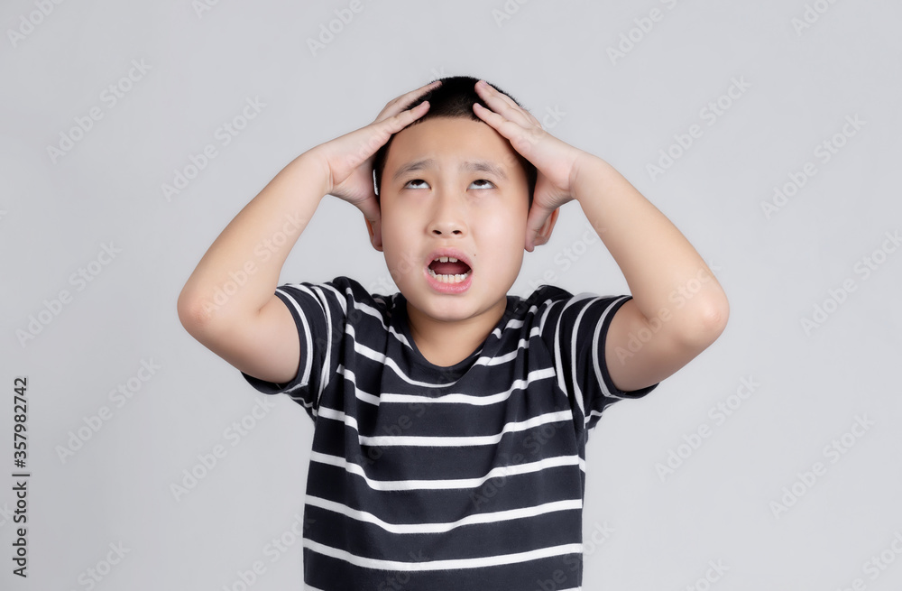 Asian boys studio portrait on gray background with hand on head for pain in head because stress. Suffering migraine.
