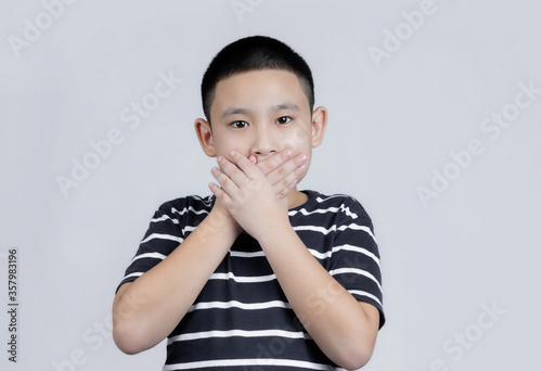 Asian boys studio portrait on gray background shocked covering mouth with hands for mistake. Secret concept.