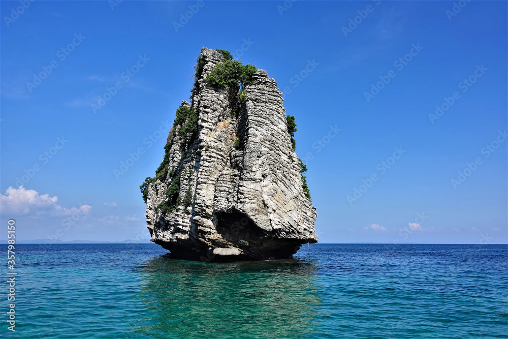 Lonely island in the Andaman Sea. A rock in the form of a pyramid rises high above the turquoise water. There are few plants on top. Reflection in water. The background is a clear bright blue sky.
Lonely island in the Andaman Sea. A rock in the form of a pyramid rises high above the turquoise water. There are few plants on top. Reflection in water. The background is a clear bright blue sky.