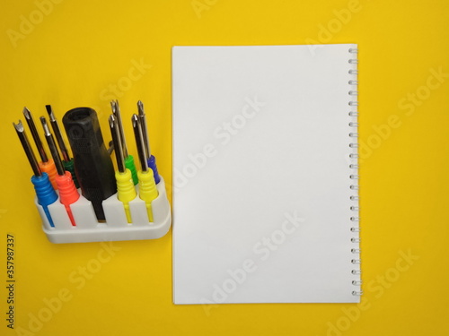 A set of multi-colored screwdrivers on a yellow background. Copy space.