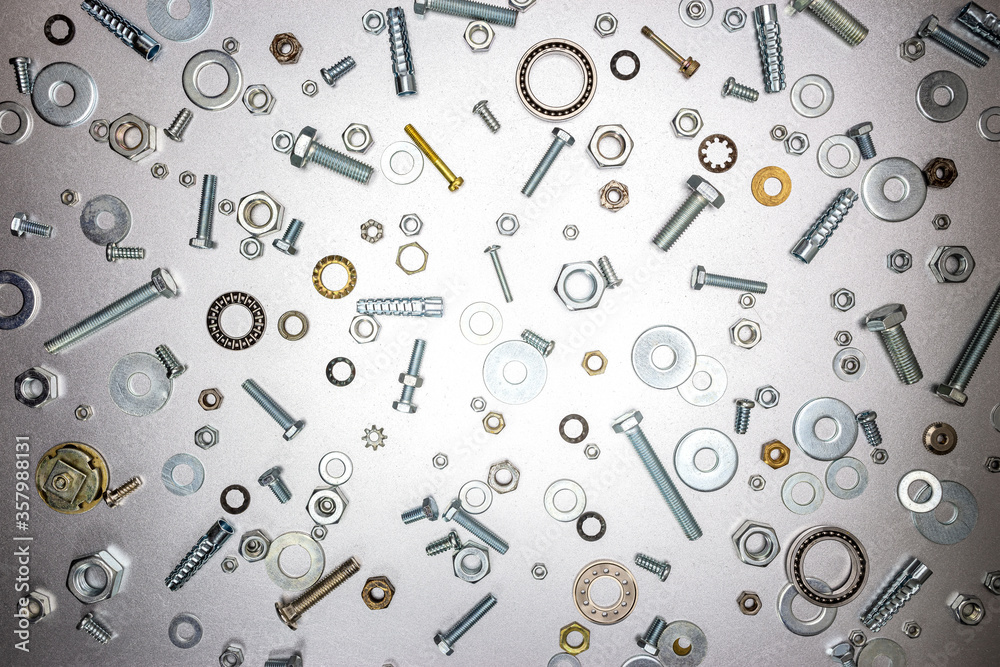different sizes of various bolts, nuts and fixing elements on gray metal surface. industrial  or home repair background