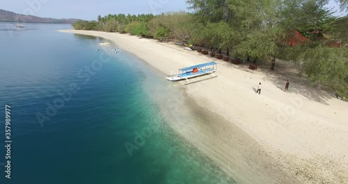 Top view of small isolated tropical island with white sandy beach and blue transparent water and speedboats, longtail boats, coral reefs, Gili Nanggu Lombok Indoneseia photo