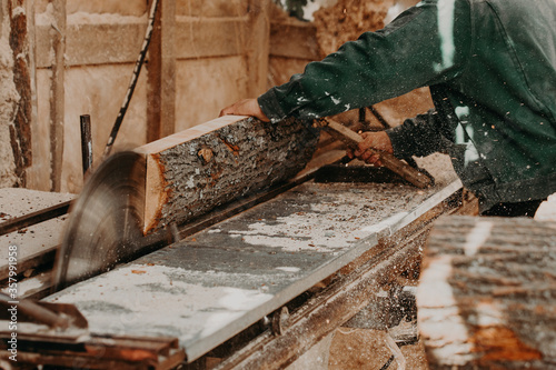Carpenter cuts wooden board on circular saw.