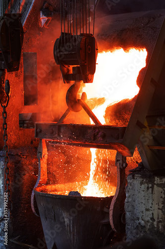 View of the big induction furnace and melting pot in foundry for smelting. The ores of base metals are often sulfides. In recent centuries, reverberatory furnaces have been used to keep the charge. photo