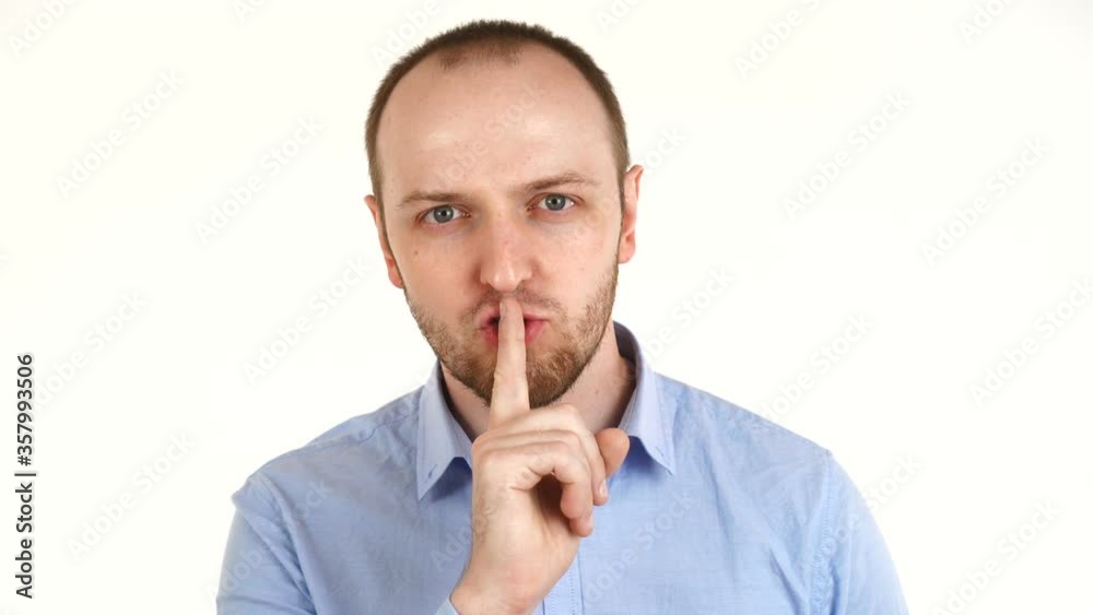 Handsome european man with finger on his lips showing hush. Portrait of guy in shirt, isolated over white background. Handsome european man with finger on his lips showing hush. Portrait of guy in shirt, isolated over white background.