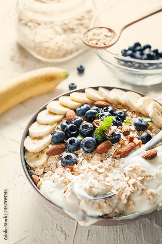 Breakfast, oatmeal with blueberry, banana almond and yogurt on a bowl in the morning.