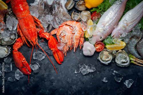 Shellfish and crustacean seafood with selection of fresh lobster, shrimp, fish, oyster, squid and crab on dark rustic background.