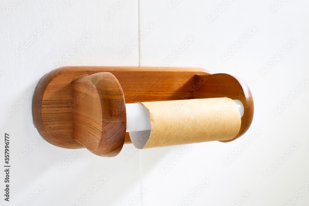 Empty toilet roll on wooden toilet paper holder.