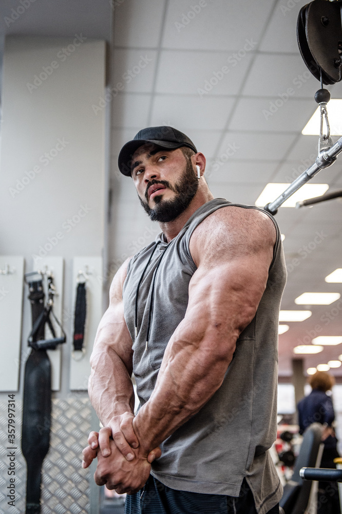 handsome young bearded man with beard wearing cap and sportswear showing  strong muscle in sport gym Stock-Foto | Adobe Stock