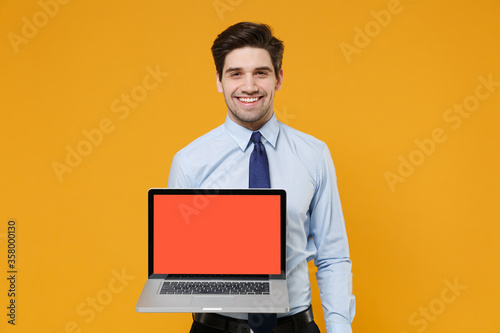 Wallpaper Mural Smiling young business man in classic blue shirt tie isolated on yellow background. Achievement career wealth business concept. Mock up copy space. Hold laptop pc computer with blank empty screen. Torontodigital.ca