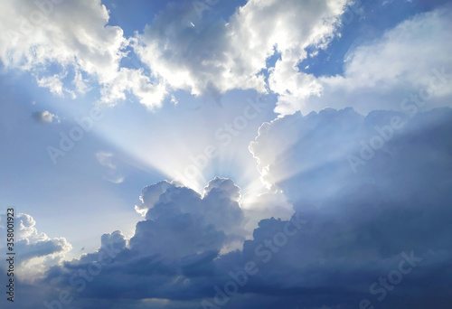 Photography The sun's rays behind the cumulus clouds in blue sky