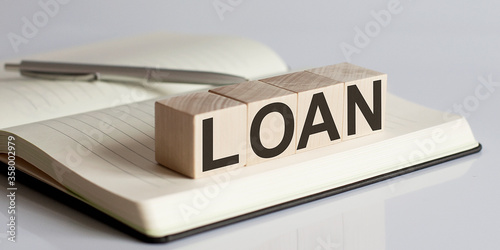 The LOAN sign on a wooden block on notebook background