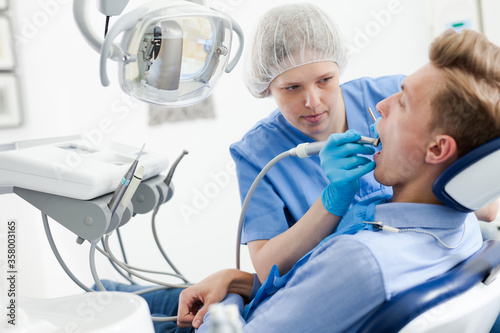 Male patient sitting on chair in dental office getting dentist treatment