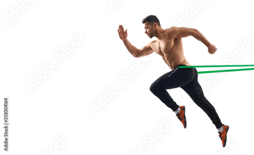 Shirtless bodybuilder running using resistance band.