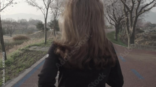 blonde girl running on road under sakura tree