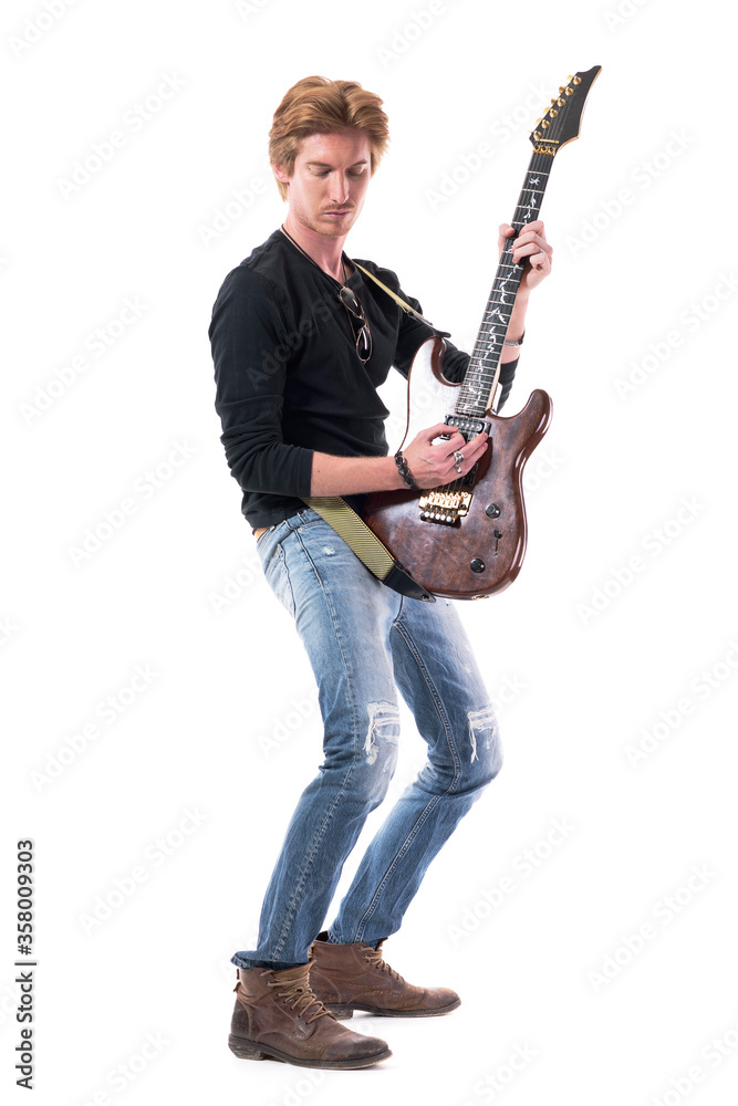 Side view of relaxed young rocker male playing electric guitar vertically looking down. Full body length isolated on white background. Side view of relaxed young rocker male playing electric guitar vertically looking down. Full body length isolated on white background.