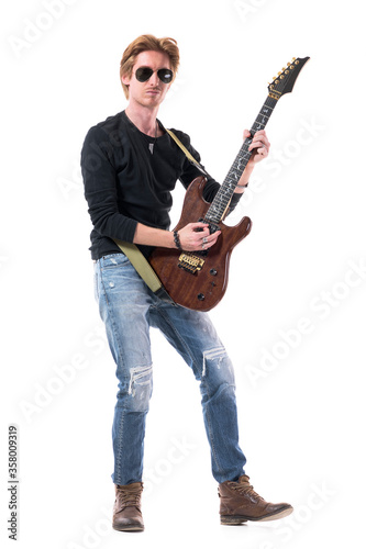 Cool redhead hard rock guitarist playing electric guitar hold in vertically. Full body length isolated on white background. 