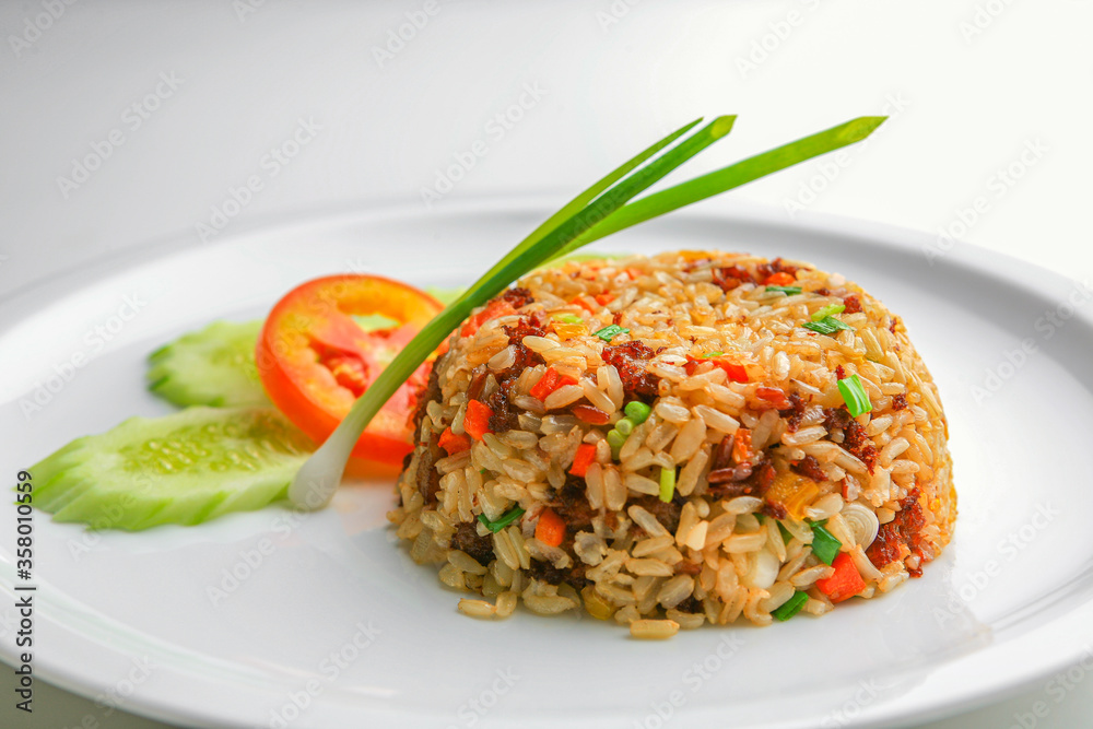 Asian fried rice with egg and vegetable in white ceramic plate on the table in the restaurant. Khao Pad popular traditional Thai style food. Front view with copy space. Asian fried rice with egg and vegetable in white ceramic plate on the table in the restaurant. Khao Pad popular traditional Thai style food. Front view with copy space.