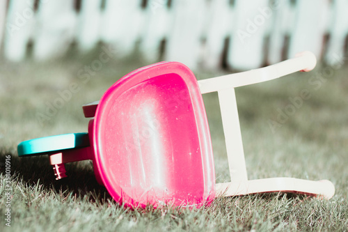 A child's wheelbarrow lies unplayed with in garden isolation. photo