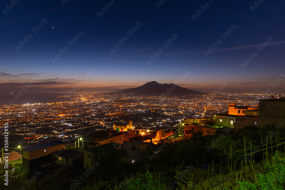 Fototapeta premium Lettere, Italy. May 12th, 2020. Panoramic view of Mount Vesuvius seen from the village of Lettere after sunset with night lights.
