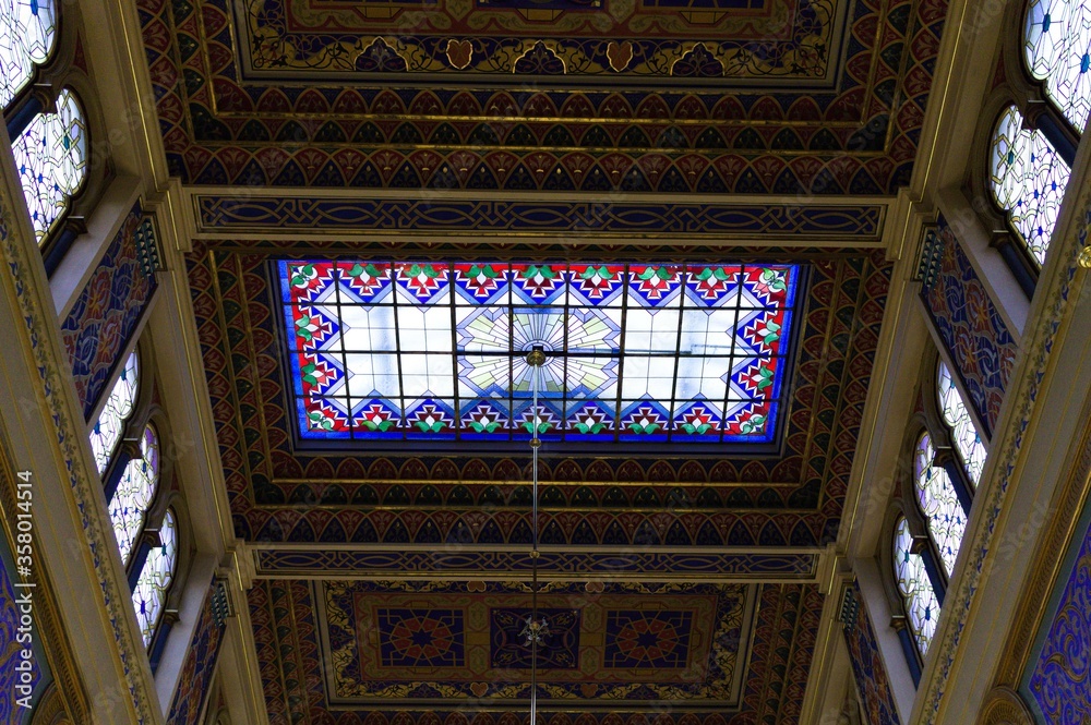 Obraz premium Prague, Czech Republic - 30 December 2019: interior of the Jeruzalémská synagoga wich has a Moorish style with many chadeliers, oriental arches, golden decorations and biblical verses on the wall