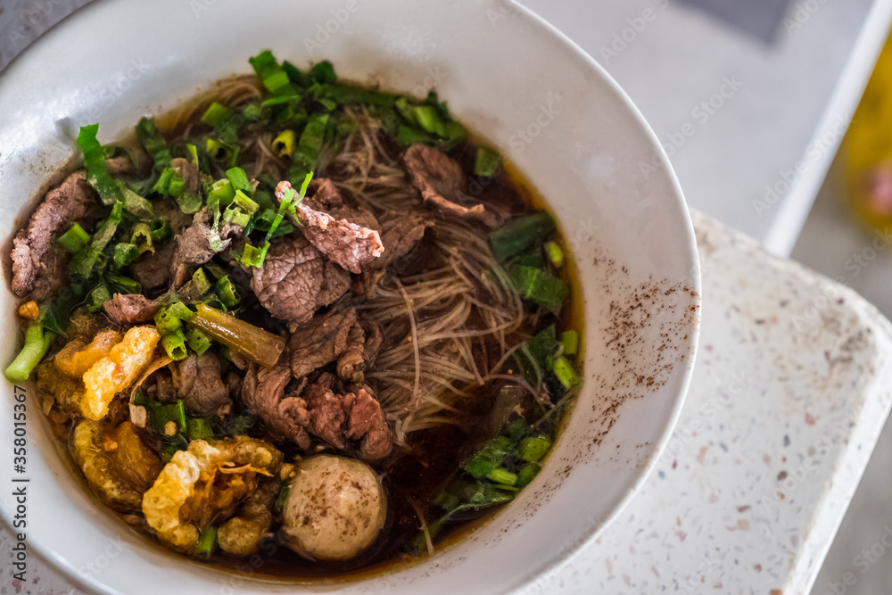 Asian noodles with cooked beef in traditional ceramic bowl. Thai peoples call Boat Noodles. Asian noodles with cooked beef in traditional ceramic bowl. Thai peoples call Boat Noodles.