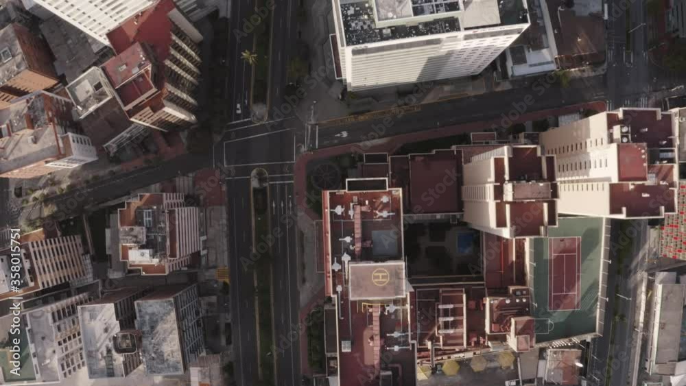 Drone shot of rooftops of houses and buildings in Avenue twelve of October in the city of Quito, Ecuador during quarantine. Overlooking empty streets with trees and no cars. Drone shot of rooftops of houses and buildings in Avenue twelve of October in the city of Quito, Ecuador during quarantine. Overlooking empty streets with trees and no cars.