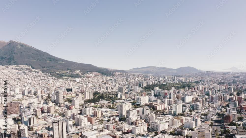 Drone shot in the north part of the city of Quito, Ecuador. Pichincha mountain, streets, houses, buildings, parks and trees. Los Andes mountain range, hills and the valleys of the city in the back. Drone shot in the north part of the city of Quito, Ecuador. Pichincha mountain, streets, houses, buildings, parks and trees. Los Andes mountain range, hills and the valleys of the city in the back.