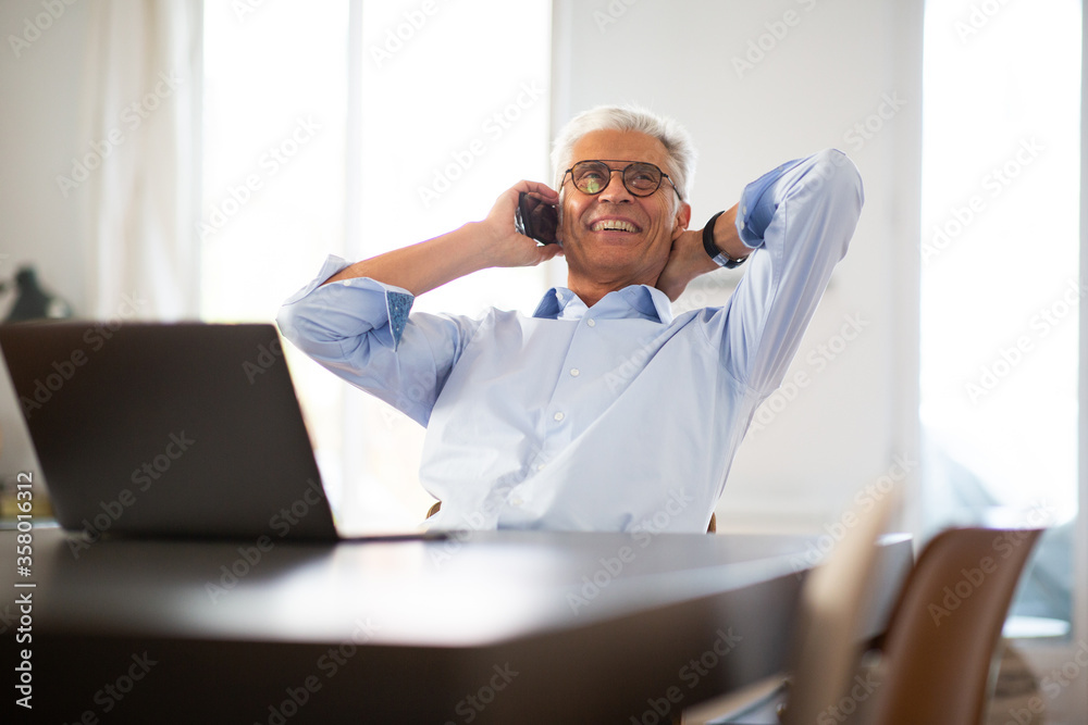 relaxed business man sitting at table talking on phone relaxed business man sitting at table talking on phone