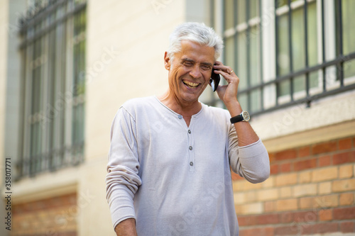 Close up older man talking with mobil phone and laughing in city