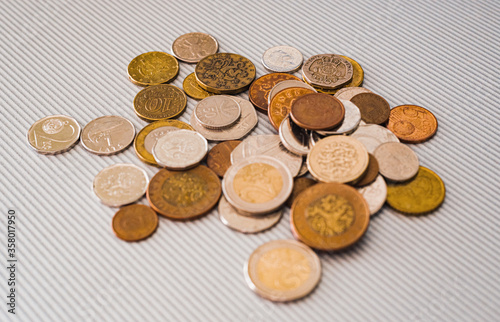 Many different coins from different countries from the black wallet are scattered around the table: dollars, pounds, rubles, pennies, cents, yuan. Saving money, losing finance, earning.