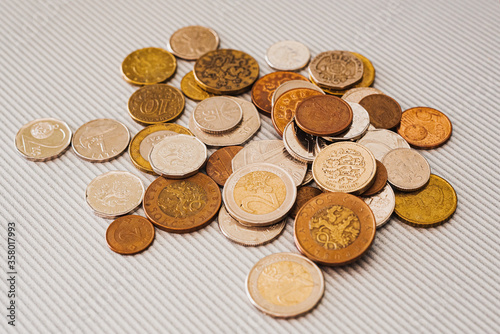 Many different coins from different countries from the black wallet are scattered around the table: dollars, pounds, rubles, pennies, cents, yuan. Saving money, losing finance, earning.