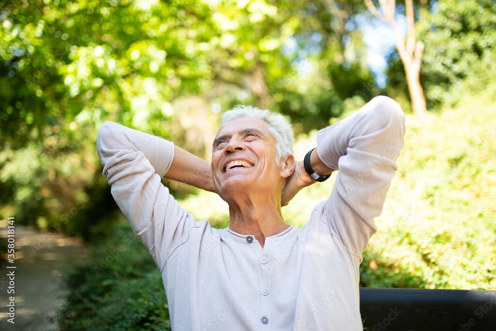 handsome older man relaxing outside with hands behind head handsome older man relaxing outside with hands behind head